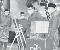  ??  ?? RASMI: Ahmad Faizal (tengah) menyempurn­akan gimik perasmian sambil disaksikan Hajiji (kanan) serta pemimpin BERSATU Sabah yang lain.