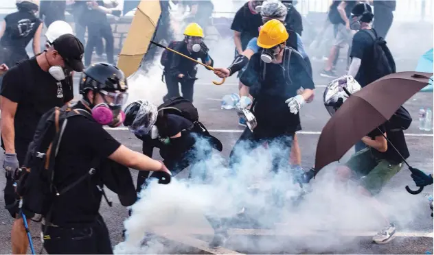  ?? Agence France-presse ?? ↑ Protesters react as police fire tear gas at them in Tai Po district, Hong Kong, on Monday.