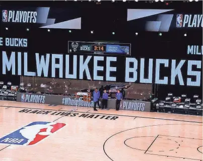  ?? KEVIN C. COX / GETTY IMAGES ?? Referees stand on an empty court on Wednesday after the Milwaukee Bucks refused to come out of their locker room for Game 5.