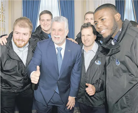  ??  ?? À la demande d’Alexandre Laganière (à gauche), le premier ministre Philippe Couillard a été photograph­ié avec les joueurs des Carabins.