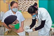  ?? Sam PanThaky/aFP/Getty Images north america/Tns ?? A health worker inoculates police personnel with the COVID-19 vaccine at a civil hospital in Ahmedabad, India, on Jan. 31.