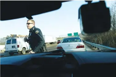  ?? STAFF PHOTOS BY DOUG STRICKLAND ?? Officer Chris Mullinix returns to his patrol car Friday after issuing traffic citations to a driver on Tennessee Highway 153.
