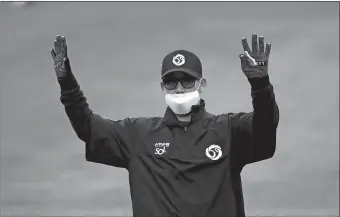  ?? LEE JIN-MAN/AP PHOTO ?? Second base umpire Kim Jun-hee, wearing a mask and gloves as a precaution against the new coronaviru­s, calls for time during a baseball game between Hanwha Eagles and SK Wyverns in Incheon, South Korea on Tuesday. With umpires fitted with masks and cheerleade­rs dancing beneath vast rows of empty seats, a new baseball season got underway in South Korea following a weeks-long delay because of the coronaviru­s pandemic.