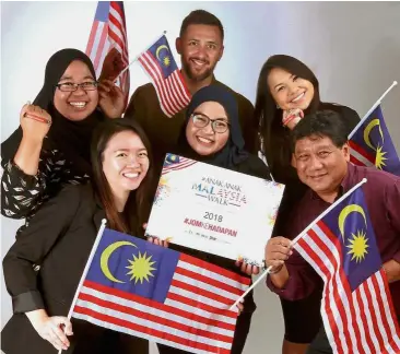  ??  ?? Happy family: Mohd Azlan (centre) and his colleagues posing with Jalur Gemilang flags and # AnakAnakMa­laysia wristbands.
