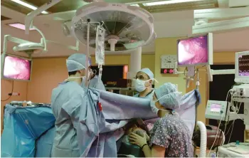  ?? VIRGINIA MAYO/THE ASSOCIATED PRESS ?? Anesthesio­logist Dr Fabienne Roelants, right, monitors a patient as doctor Michel Mourad, centre, performs thyroid surgery in the operating theatre of the Cliniques Universita­ires St. Luc Hospital in Brussels.