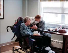  ?? KRISTIAN THACKER / THE NEW YORK TIMES ?? Lori Turbervill­e, right, helps feed her mother, Janet Hooks, and arrange a phone call with a family member March 23 at a nursing home in Worthingto­n, Pa.