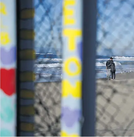  ??  ?? Two people embrace on the US side of the border, seen through the border fence along the beach in Tijuana, Mexico. US President Donald Trump will visit the border on Friday