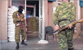  ?? JOHN MACDOUGALL/AGENCE FRANCE-PRESSE VIA GETTY IMAGES ?? Guards of the self-proclaimed “Donetsk People’s Republic” keep watch Tuesday in the town hall of the besieged Ukrainian city of Slavyansk.