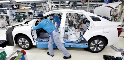  ?? REUTERS ?? EMPLOYEES of Toyota Motor Corp. pushes a body unit of a Mirai fuel cell vehicle (FCV) on it’s assembly line at the company’s Motomachi plant in Toyota, Aichi prefecture, Japan, May 17.