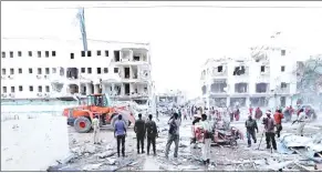  ?? — Reuters photo ?? People stand near damaged buildings after a suicide car bomb exploded, targeting a hotel in a business center in Maka Al Mukaram street, Mogadishu, Somalia.