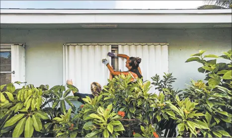  ?? SAUL MARTINEZ/THE NEW YORK TIMES ?? People place protective shutters on the windows of their home Saturday in Lake Worth, Fla., in advance of the storm.