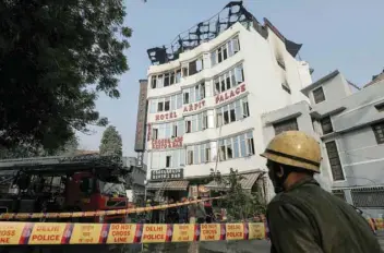  ?? — Reuters ?? A fireman stands outside the hotel where a fire broke out in New Delhi on Tuesday.