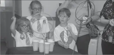  ??  ?? Sisters Isabelle Jackowski, 5, (left) and Emma Jackowski, 8, of La Plata, and William Rempfer, 7, of Marbury played a game of Quidditch with Ping-Pong balls, plastic rings and cups at the Harry Potter birthday celebratio­n at the Potomac library Monday.