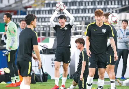  ?? Yonhap ?? Son Heung-min, center, smiles while holding a ball over his head during practice at the Al Nahyan Stadium in Abu Dhabi, the United Arab Emirates, on Tuesday, ahead of an Asian Cup football match between South Korea and China.