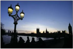  ?? (AP) ?? People stand on Westminste­r Bridge to watch the sun go down over Parliament in London on Jan. 16.