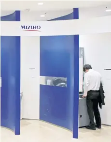  ?? REUTERS ?? A man uses an ATM machine of Mizuho bank in Tokyo.