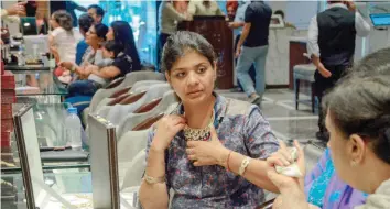  ?? AFP ?? A customer tries on gold jewellery at a store in Amritsar. Dhanteras is seen as an auspicious day on which to make purchases.