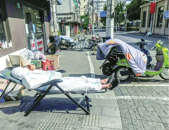  ?? EFE ?? Un repartidor de comida a domicilio descansa en plena calle en Shanghai