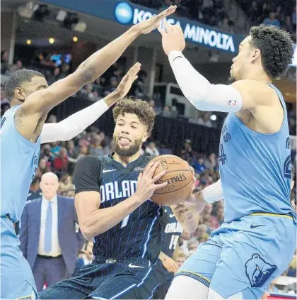  ?? BRANDON DILL/AP ?? Magic guard Michael Carter-Williams drives between Grizzlies guards Josh Jackson (20) and Dillon Brooks during Tuesday night’s game.