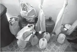  ?? Associated Press ?? ■ This photo taken Tuesday shows dozens of gallon jugs and plastic buckets used to store water for bathing in the home of Antonio Morales in Corozal, Puerto Rico. Nearly six months ago, Hurricane Maria shredded the electric poles in this plantain...