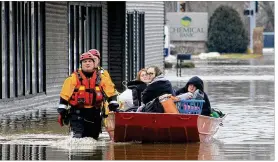  ?? BEN MIKESELL / AP ?? Firefighte­rs in Goshen, Ind., pull a boat holding three women who were rescued from a group home on Wednesday afternoon. Record flooding also closed down a wastewater plant in South Bend for several hours.