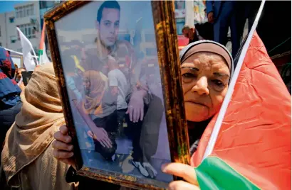 ?? AFP ?? A woman holds the portrait of a Palestinia­n prisoner during a rally in the West Bank city of Ramallah to show support to Palestinia­ns detained in Israeli jails after hundred of them launched a hunger strike. —