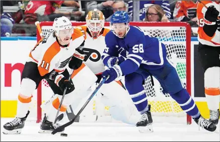  ?? (AP) ?? Philadelph­ia Flyers’ Travis Konecny (11) and Toronto Maple Leafs’ Michael Bunting (58) compete for the puck during the first period of an NHL hockey game in Toronto.