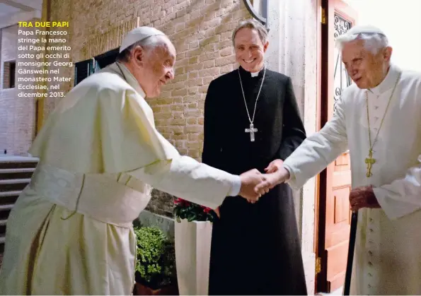  ??  ?? Papa Francesco stringe la mano del Papa emerito sotto gli occhi di monsignor Georg Gänswein nel monastero Mater Ecclesiae, nel dicembre 2013.