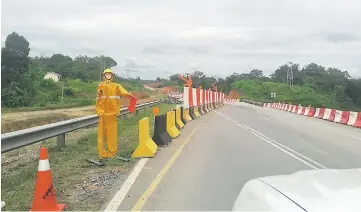  ??  ?? The ‘constructi­on worker mannequin’ at a road stretch, waving and signalling at motorists to prevent them from knocking over it.