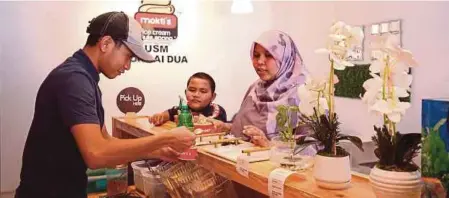  ?? ?? MUHAMMAD Afiq melayan pelanggan yang mahu menikmati aiskrim di tempat kerjanya di Sungai Dua, Georgetown. - Gambar NSTP/MIKAIL ONG