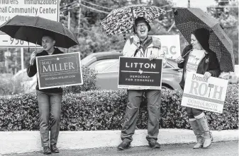  ?? Michael Ciaglo / Staff photograph­er ?? Hosseh Enad, from left, Lee Bryant and Sara Garcia stand under their umbrellas as they campaign outside the Trini Mendenhall Community Center for the second day of early voting.