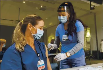  ?? HANS GUTKNECHT — SOUTHERN CALIFORNIA NEWS GROUP ?? Emergency room physician Dr. Stephanie Rubio receives a COVID-19 vaccinatio­n from nurse Leslee Hernandez at Kaiser Permanente Woodland Hills Medical Center on Dec. 17. Vaccines offer hope, but not an immediate return to normal.