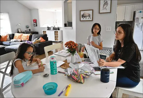  ?? PHOTOS BY HYOSUB SHIN/HYOSUB.SHIN@AJC.COM ?? Mary Martinez, a Sugar Hill mother of three, helps daughters Sabrina (left), 7, and Laila, 8, while trying to finish her own schoolwork. Martinez was a retail sales associate before the pandemic, but she was tired of a paycheck that barely covered child care costs. She enrolled part-time at Georgia Perimeter College.