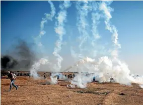  ?? AP ?? Palestinia­n protesters run for cover from tear gas fired by Israeli troops at the Gaza Strip’s border with Israel, a day after Israeli troops firing from across a border fence killed dozens of Palestinia­ns and wounded more than 2700 at a mass protest...