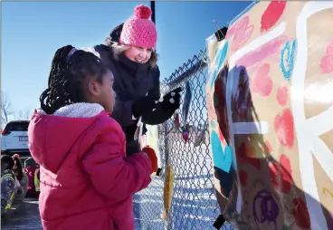  ?? HERALD PHOTO BY ALEJANDRA PULIDO-GUZMAN ?? Kindergart­en teacher Laurie McIntosh and kindergart­en student Pelia Hene hang heart art Tuesday morning during the fifth annual Take What You Need event at The Children of St. Martha’s Elementary School.