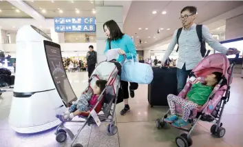  ?? AP FOTO ?? AID. A tourist talks with Troika, a selfdrivin­g robot made by LG Electronic­s, at the Incheon Internatio­nal Airport in South Korea. Robots help travelers find their boarding gates and keep airport floors clean.