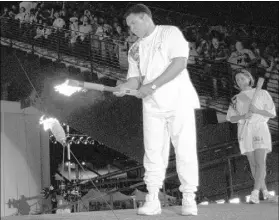  ?? MICHAEL PROBST/THE ASSOCIATED PRESS FILE ?? In the most indelible moment of the 1996 Olympic Games in Atlanta, former boxer Muhammad Ali lights the Olympic flame during the opening ceremony. Swimmer Janet Evans, the penultimat­e torch bearer, waits in the background in case Ali has trouble...