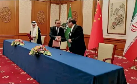  ?? AP ?? Chinese Foreign Minister Wang Yi congratula­tes Ali Shamkhani, secretary of Iran’s Supreme National Security Council, right, and Saudi Arabia’s National Security Adviser Musaad bin Mohammed al-Aiban at the signing of their agreement in Beijing yesterday.