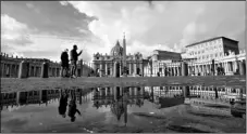  ?? AP Photo/Alessandra Tarantino ?? In this Jan. 31 file photo, people are reflected on a puddle as they walk in St. Peter’s Square, at the Vatican.