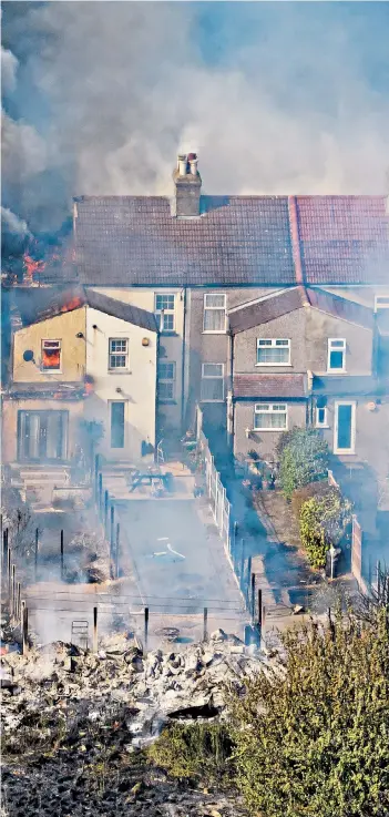  ?? ?? Fires broke out in several areas in yesterday’s intense heat. Below, clockwise from main picture: a row of houses engulfed by the blaze in Wennington, Essex; police officers lead horses to safety in the village; flames at the edge of the A2 in Kent; gorse smoulders near Zennor, Cornwall