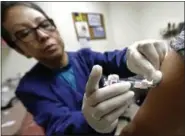  ?? TED S. WARREN — THE ASSOCIATED PRESS ?? Ana Martinez, a medical assistant at the Sea Mar Community Health Center, gives a patient a flu shot, Thursday in Seattle.