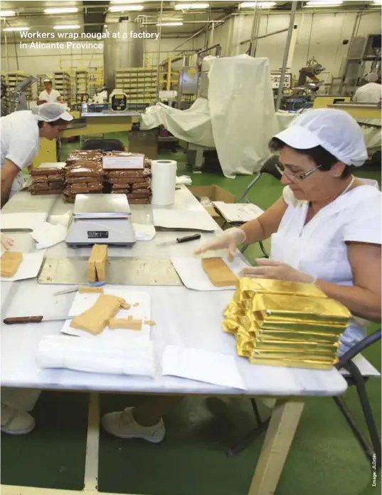  ?? ?? Workers wrap nougat at a factory in Alicante Province