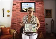  ?? AP PHOTO BY CARLOS GIUSTI ?? Nerybelle Perez poses with a portrait of her father, World War II veteran Efrain Perez, who died inside an ambulance after being turned away from the largest public hospital when it had no electricit­y or water, days after Hurricane Maria passed, in...