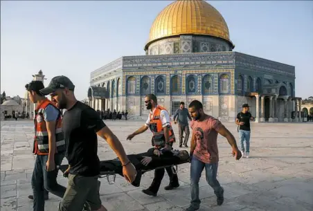  ?? Ahmad Gharabli/AFP/Getty Images ?? Palestinia­n paramedics carry an injured woman on a stretcher past the Dome of the Rock Thursday after clashes broke out inside Al-Aqsa mosque’s compound in Jerusalem’s Old City. Clashes erupted between Israeli police and Palestinia­ns at the sensitive...