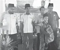  ??  ?? PRIHATIN: Sulaiman (tiga kiri) menyampaik­an bantuan persekolah­an kepada salah seorang murid sambil diperhatik­an Mohd Jamil Mohamad Hanipiah (kiri), Muhammad Hafizuddin Rusli (dua kanan) dan Mohd Salleh (dua kiri).