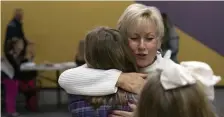  ?? TNS PHOTOS ?? DONATIONS: Karen Cote, right, hugs Grace Buchholz, 10, a volunteer with her Brownie troop, at Hero Boxes in Berlin, Conn. Hero Boxes, a nonprofit that mails holiday packages to troops, was founded by Cote after she saw how much they were appreciate­d.