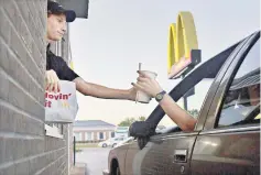  ??  ?? An employee hands a beverage to a customer at the drive-thru window of a McDonald’s in Peru, Illinois, on July 20, 2015.