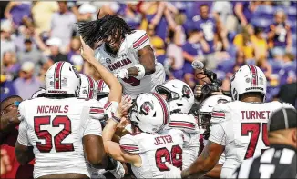  ?? KARL B DEBLAKER/ASSOCIATED PRESS ?? South Carolina’s Cam Smith (9) jumps on top of teammates celebratin­g their victory over East Carolina at the end of Saturday’s game in Greenville, N.C.