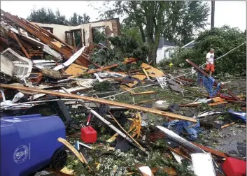  ?? TIM BATH/THE KOKOMO TRIBUNE VIA AP ?? A man walks through debris after a tornado in Kokomo, Ind., on Wednesday. Multiple tornadoes touched down in central Indiana on Wednesday, tearing the roofs off apartment buildings, sending air conditione­rs falling onto parked cars and cutting power to...