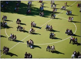  ?? (AP/dpa/Kay Nietfeld) ?? At a German high school graduation ceremony Tuesday in Berlin, graduates and their relatives sit for the ceremony in designated spaces on a playing field.